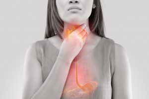Woman holding throat due to acid reflux