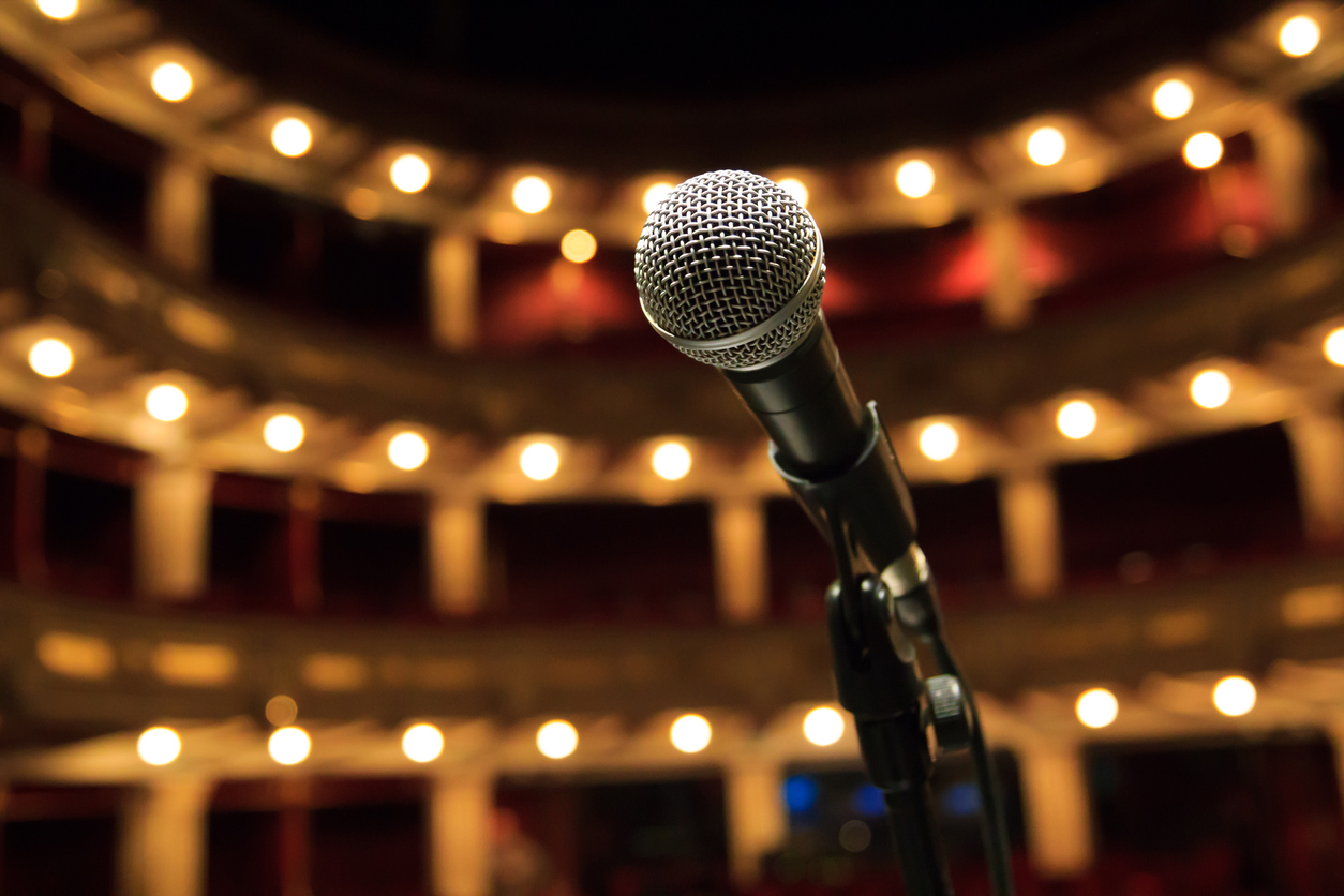 Vocal microphone on stand on stage, looking out into a concert hall