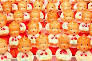 A large choir of cute small dolls that look like they are singing in traditional red and white choir robes