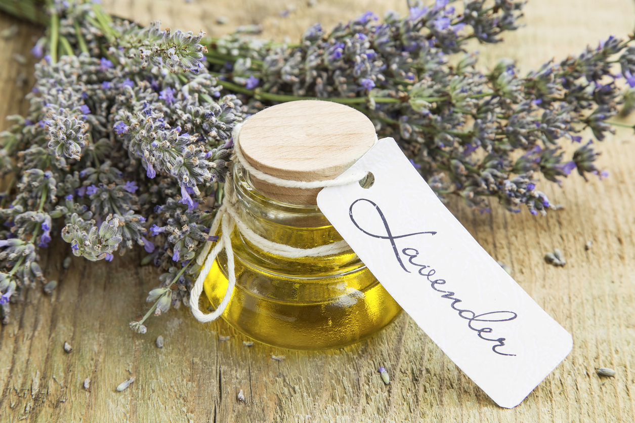 Lavender oil with label and flowers on rustic background